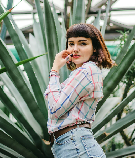 woman with clear skin next to aloe vera plant